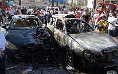 A firefighter extinguishes a burned car close to where an explosion went off between the buildings of the Ministry of Information and the Ministry of Justice in Damascus, Syria. (photo credit: AP Photo/SANA)