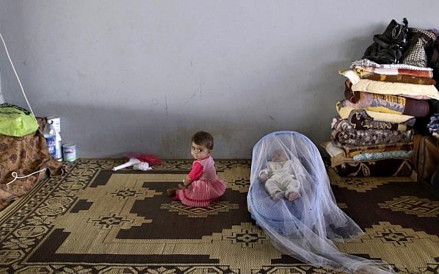 A Syrian child whose family fled their home in Aleppo 15 days ago, sits next to her one-month-old brother on Thursday, as they take refuge with their family at the Bab Al-Salameh border crossing, in the hopes of entering one of the refugee camps in Turkey. (photo credit: AP/Muhammed Muheisen)