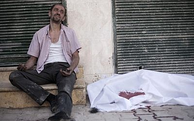 A man cries near the body of his brother, killed by a Syrian Army sniper, in Aleppo on Thursday (photo credit: AP/Manu Brabo)