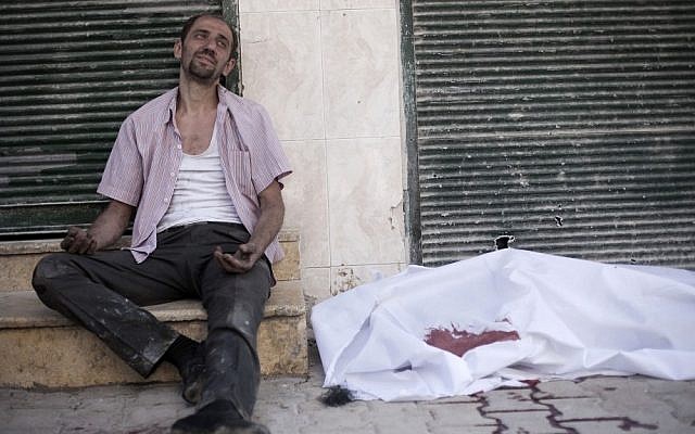 A man cries near the body of his brother, killed by a Syrian Army sniper, in Aleppo on Thursday (photo credit: AP/Manu Brabo)