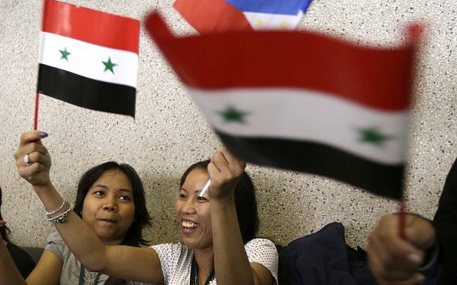 Overseas Filipino Workers, who fled the civil war in Syria, wave Syrian and Philippine flags upon arriving at the Ninoy Aquino International Airport in Manila via a chartered flight by the International Organization for Migration on Tuesday, September 11, 2012 (Photo credit: AP/Bullit Marquez) Overseas Filipino Workers, who fled the civil war in Syria, wave Syrian and Philippine flags upon arriving at the Ninoy Aquino International Airport in Manila via a chartered flight by the International Organization for Migration on Tuesday, September 11, 2012 (Photo credit: AP/Bullit Marquez)