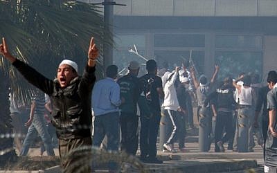 Protesters wave a flag while standing atop the security post of the main entrance to the US embassy in Tunis, Tunisia, last month. (photo credit: AP)