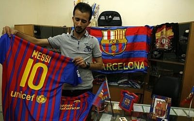 A Palestinian vendor stands among flags and shirts of Barcelona's football team at a sporting goods store in Rafah, in the southern Gaza strip, on September 29 (photo credit: Abed Rahim Khatib/Flash90)