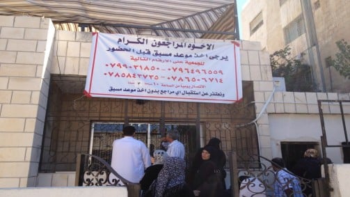 A banner outside the locked offices of Nidaa Al-Kheir asks refugees to schedule an appointment before arriving to pick up aid packages (photo credit: Elhanan Miller/Times of Israel)