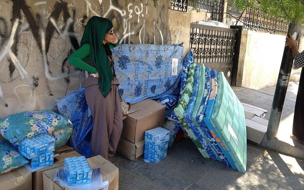 A Syrian refugee stands next to a pile of mattresses and packaged milk in Amman, given out as aid to refugees, Amman, September 23 (photo credit: Elhanan Miller/Times of Israel) A Syrian refugee stands next to a pile of mattresses and packaged milk in Amman, given out as aid to refugees, Amman, September 23 (photo credit: Elhanan Miller/Times of Israel)