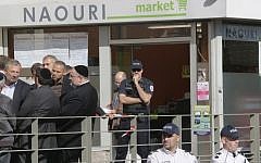 Police and members of the Jewish community stand in front of a kosher supermarket in Sarcelles, north of Paris, where a bomb exploded last month (photo credit: AP/Michel Euler)