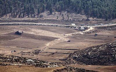 Army vehicles and helicopters are seen in an open area as they search for the remains of a drone in the Negev Saturday. (photo credit: AP/Yehuda Lachiani)