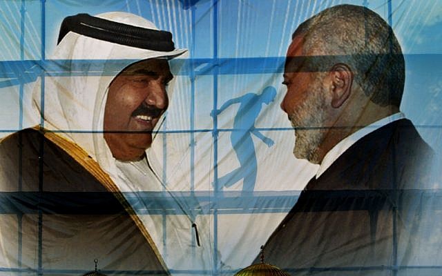 A Palestinian worker walks behind posters of the Emir of Qatar Sheikh Hamad bin Khalifa al-Thani, left, and Gaza's Hamas Prime Minister Ismail Haniyeh, right, in preparation for the upcoming visit to Gaza at Palestine stadium in Gaza City, Monday, Oct. 22, 2012. (photo credit: Adel Hana/AP)