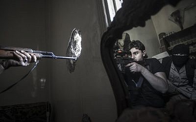 In this Monday, Oct. 29, 2012 photo, a rebel sniper aims at a Syrian army position, seen with another rebel fighter reflected in a mirror, in a residential building in the Jedida district of Aleppo, Syria (photo credit: AP Photo/Narciso Contreras)