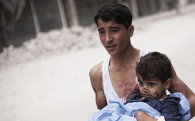 A Syrian youth holds a child wounded by Syrian Army shelling in Aleppo on Thursday (photo credit: AP/Manu Brabo)