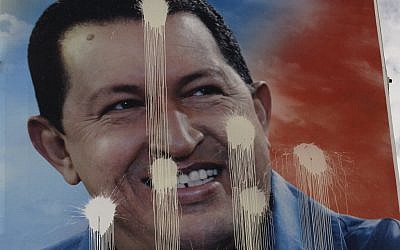 A defaced election campaign poster of Venezuela's President Hugo Chavez hangs in Caracas, Venezuela (photo credit: Fernando Llano/AP)