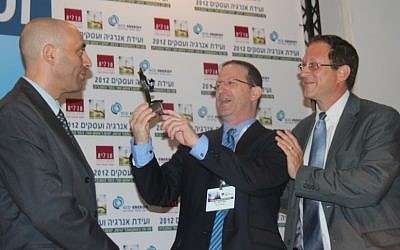 Shaul Tzemach, Directory General of the Ministry of Energy and Water, looks on as Dr. Amit Mor, Co-CEO of Eco Energy, presents Yosef Abramowitz, President of Arava Power Company, the 2012 Energy and Business Convention Person of the Year Award for the accomplishments of the Arava Power team in developing the solar power industry in Israel. (Photo credit: Hannah Schafer)