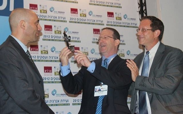 Shaul Tzemach, Directory General of the Ministry of Energy and Water, looks on as Dr. Amit Mor, Co-CEO of Eco Energy, presents Yosef Abramowitz, President of Arava Power Company, the 2012 Energy and Business Convention Person of the Year Award for the accomplishments of the Arava Power team in developing the solar power industry in Israel. (Photo credit: Hannah Schafer) Shaul Tzemach, Directory General of the Ministry of Energy and Water, looks on as Dr. Amit Mor, Co-CEO of Eco Energy, presents Yosef Abramowitz, President of Arava Power Company, the 2012 Energy and Business Convention Person of the Year Award for the accomplishments of the Arava Power team in developing the solar power industry in Israel. (Photo credit: Hannah Schafer)