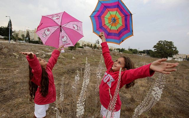 Israeli children running with umbrellas during the first rain of the year. (photo credit: Edi Israel/Flash90)