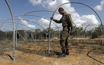 An Israeli army officer examines the area near the Israel-Gaza border, after it was hit by a mortar shell fired by Palestinian terrorists. (photo credit: Tsafrir Abayov/Flash90)