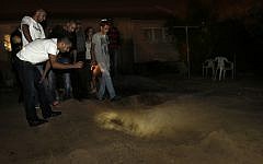 People inspecting a crater left in the backyard of a Netivot home after a Grad rocket crashed into it. (photo credit: Tsafrir Abayov/Flash90)