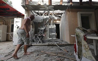 A man examines a damaged house after a rocket fired by Palestinian terrorists from the Gaza Strip hit a community in southern Israel, October 24, 2014 (photo credit: Tsafrir Abayov/Flash90)