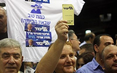 A member of Likud raises a yellow note in favor of the joint Likud-Yisrael Beytenu Knesset list, Monday at the Likud Central Committee meeting (photo credit: Roni Schutzer/Flash90)