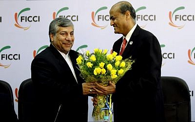 Federation of Indian Chambers of Commerce and Industry President, R. V. Kanoria, right, greets Iranian Energy Minister Majid Namjoo with a bouquet of flowers before an interactive business meeting in New Delhi, India on Wednesday. (photo credit: AP/Altaf Qadri)