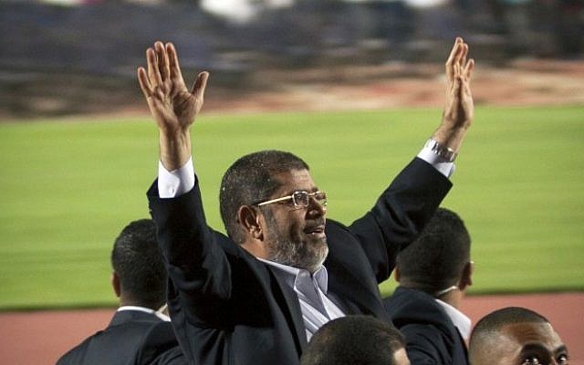 Egyptian President Mohammed Morsi waves to a crowd gathered at a Cairo stadium. (photo credit: AP)