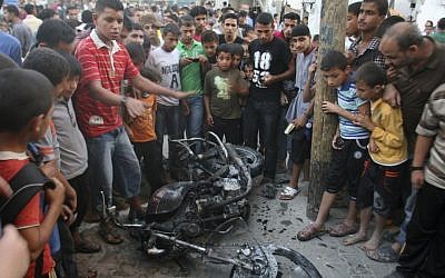 Palestinians gather a round the wreckage of motorcycle following an Israeli air strike in Rafah, southern Gaza Strip, Sunday. Israel said it fired on two Gaza members of an al-Qaida-inspired terror group; one was killed. (photo credit: AP Photo/Eyad Baba)