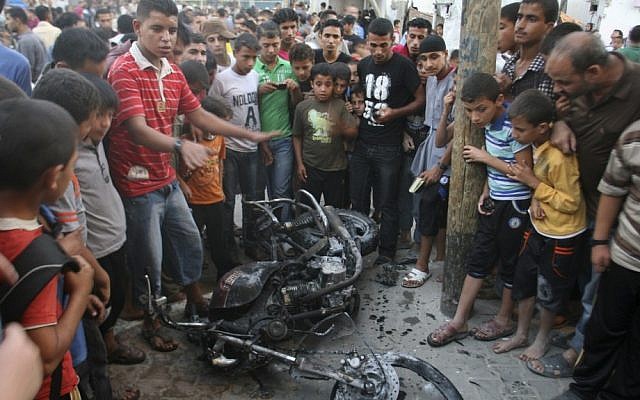 Palestinians gather a round the wreckage of motorcycle following an Israeli air strike in Rafah, southern Gaza Strip, last Sunday. (photo credit: AP Photo/Eyad Baba)