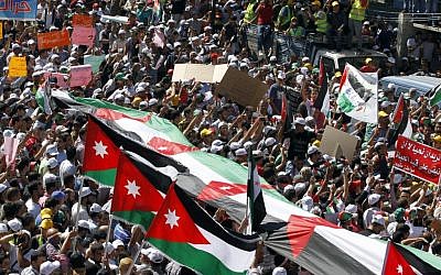 Thousands of Islamic Action Front supporters carrying banners and a large Jordanian flag gather earlier this month to demand constitutional reforms during an opposition rally in Amman. (photo credit: AP/Raad Adayleh)