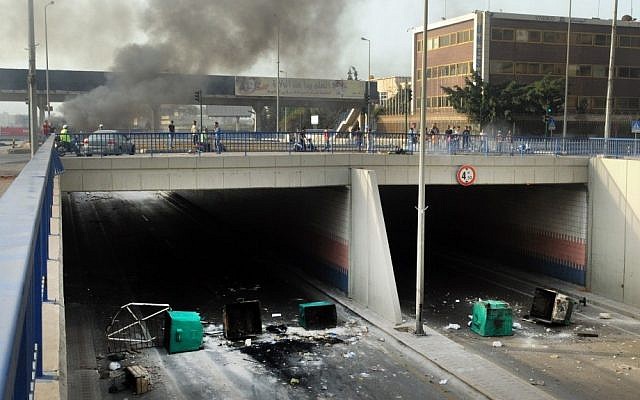 A highway link to Beirut International airport is blocked by garbage containers overturned and set aflame on Saturday by Sunni protesters angry at the killing of Brig. Gen. Wissam al-Hassan last year. (photo credit: AP/Ahmad Omar)
