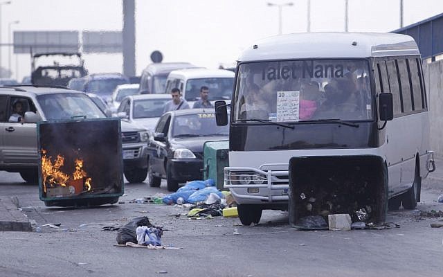 A bus pushes a garbage container used as a roadblock by Sunni protesters after overnight clashes between Sunni and Shiite gunmen in Beirut, Lebanon on Monday. (photo credit/Hussein Malla/AP) A bus pushes a garbage container used as a roadblock by Sunni protesters after overnight clashes between Sunni and Shiite gunmen in Beirut, Lebanon on Monday. (photo credit/Hussein Malla/AP)