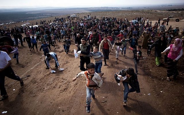 Displaced Syrian children run after a truck loaded with presents for Eid Al-Adha in a refugee camp in Idlib province, Syria, l(AP/Manu Brabo)