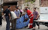 Men carry the body of a casualty in an attack against a government compound in Aleppo Wednesday (photo credit: AP Photo/SANA)