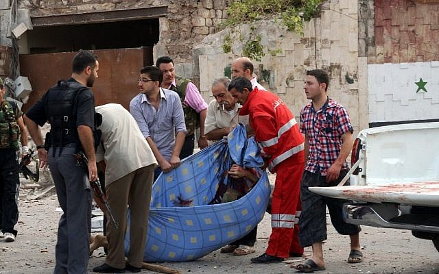 Men carry the body of a casualty in an attack against a government compound in Aleppo Wednesday (photo credit: AP Photo/SANA)