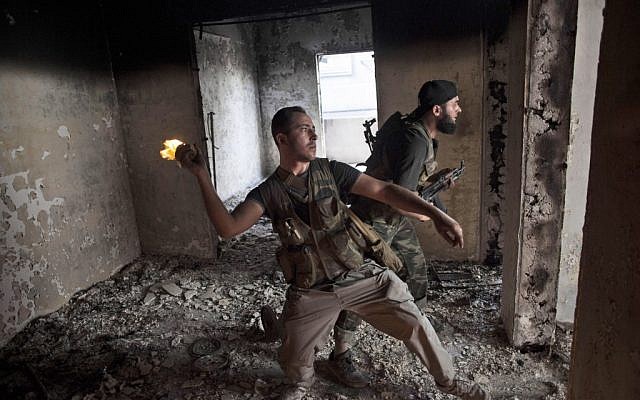 Free Syrian Army soldier throws a petrol bomb at Syrian Army positions in Saif Al Dawle district in Aleppo, October 3 (photo credit: AP/ Manu Brabo)