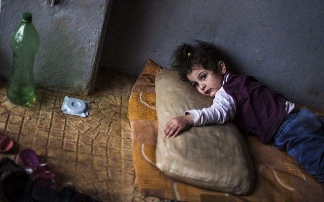 Rada Hallabi, 4, who is sick with diabetes, lies on a blanket in a refugee camp on Syria's border with Turkey, near the Azaz village, on Sunday. (photo credit: Manu Brabo/AP)