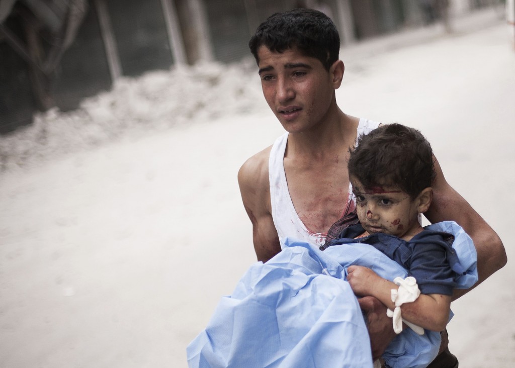 In this Thursday, Oct. 11, 2012 photo, a Syrian youth holds a child wounded by Syrian Army shelling near Dar al-Shifa hospital in Aleppo, Syria (AP Photo/ Manu Brabo)