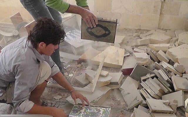 Syrian citizens remove copies of the Quran from under the rubble of a mosque destroyed by government shelling in Idlib province, northern Syria (photo credit: AP/Idlib News Network ENN)