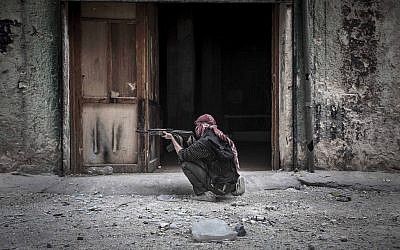 A Free Syrian Army fighter sights a government position as rebel fighters belonging to the Liwa Al Tawhid group carry out a military operation in Aleppo, Syria. (photo credit: AP/Narciso Contreras)