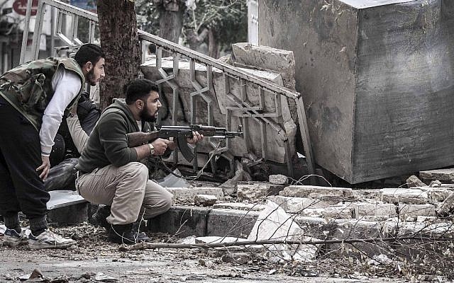 Syrian rebel fighters take cover as a Syrian army sniper fires from a destroyed mosque in Tarik Al-Bab, southeast of Aleppo, Syria on Friday, October 26. (photo credit: AP/Narciso Contreras)