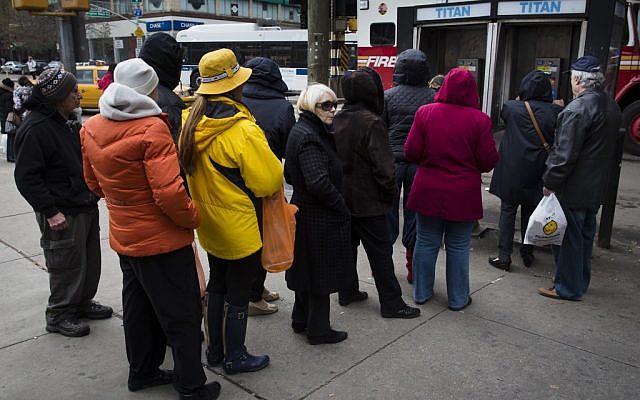 People wait to use a pay phone on Bright Beach Avenue, Wednesday, Oct. 31, 2012, in the Brooklyn borough of New York. People in the coastal corridor battered by superstorm Sandy took the first cautious steps Wednesday to reclaim routines upended by the disaster, even as rescuers combed neighborhoods strewn with debris and scarred by floods and fire. (John Minchillo/AP)