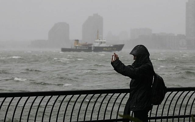 A woman uses her mobile phone to photograph stormy New York Harbor at Battery Park, the southern tip of Manhattan, on Monday, October 29, 2012 (photo credit: AP Photo/Richard Drew)