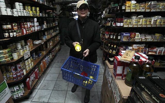 A woman shops for groceries by flashlight in the Tribeca neighborhood of New York, Tuesday, Oct. 30, 2012. (photo credit: Richard Drew/AP)