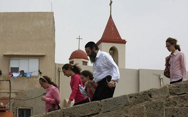 A religious Jewish family walks past a church in Acre's Old City (photo credit: Nati Shohat/Flash90)