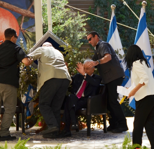 President Peres's bodyguards lifting a sign from him after it fell on him inside his sukkah on Wednesday (photo credit: Sharon Marks Altshul) President Peres's bodyguards lifting a sign from him after it fell on him inside his sukkah on Wednesday (photo credit: Sharon Marks Altshul/The Real Jerusalem Streets)