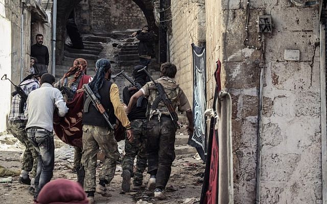 A group of Free Syrian Army fighters carry a wounded comrade to cover in the town of Harem, Syria on October 30.  (photo credit: AP/Mustafa Karali)