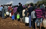 Syrian refugees line up to fill plastic containers with water at a displaced persons camp near the Turkish border, November 2012 (photo credit: AP/Khalil Hamra/File)