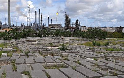 Graves at the Beth Haim cemetery on the outskirts of Willemstad, Curacao, are backdropped by the Isla oil refinery (photo credit: AP/Karen Attiah)