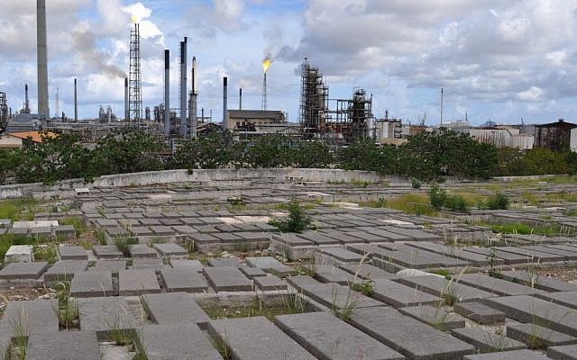 Graves at the Beth Haim cemetery on the outskirts of Willemstad, Curacao, are backdropped by the Isla oil refinery (photo credit: AP/Karen Attiah)