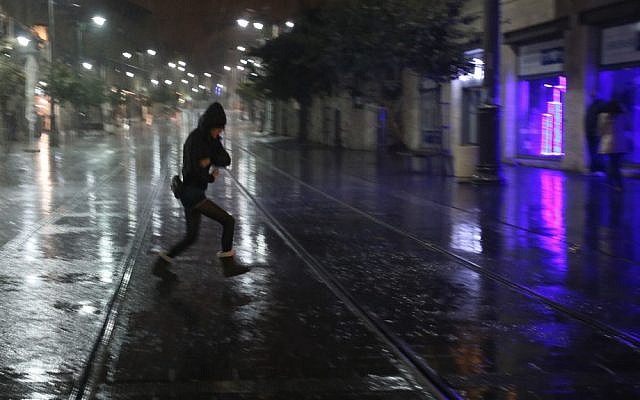 An Israeli woman runs for cover as the first rain of the year falls on Jerusalem on Friday (photo credit: Oren Nahshon/Flash90)