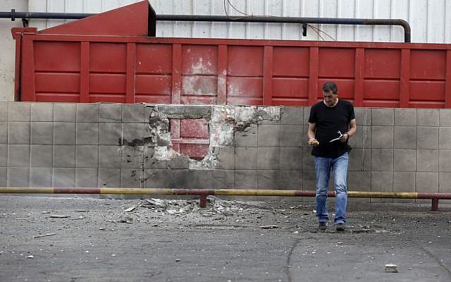 Israeli police sappers remove a pipe from an exploded missile that slammed into a factory wall in the southern Israeli town of Sderot, 11 November 2012 (photo credit: Tsafrir Abayov/Flash90) Israeli police sappers remove a pipe from an exploded missile that slammed into a factory wall in the southern Israeli town of Sderot, 11 November 2012 (photo credit: Tsafrir Abayov/Flash90)