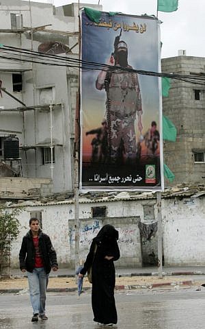 Palestinians walk next to past murals depicting slogans for Hamas in the Rafah refugee camp on Monday.(photo credit: Abed Rahim Khatib/Flash 90)
